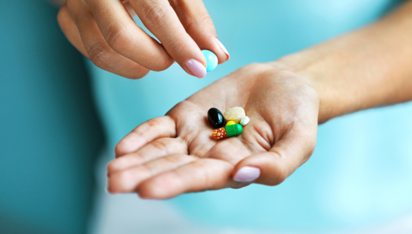 A woman who heard about supplements everyone should take holds out a handful of various colorful pills and capsules.