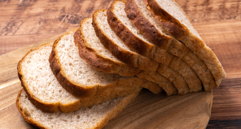 Freshly sliced white bread loaf arranged on wooden cutting board.