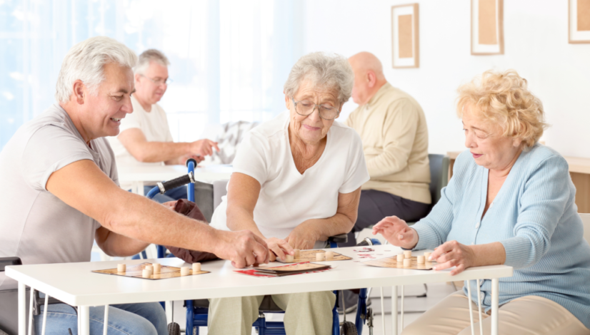 Senior adults playing board games together in a bright facility, promoting social interaction and engagement.