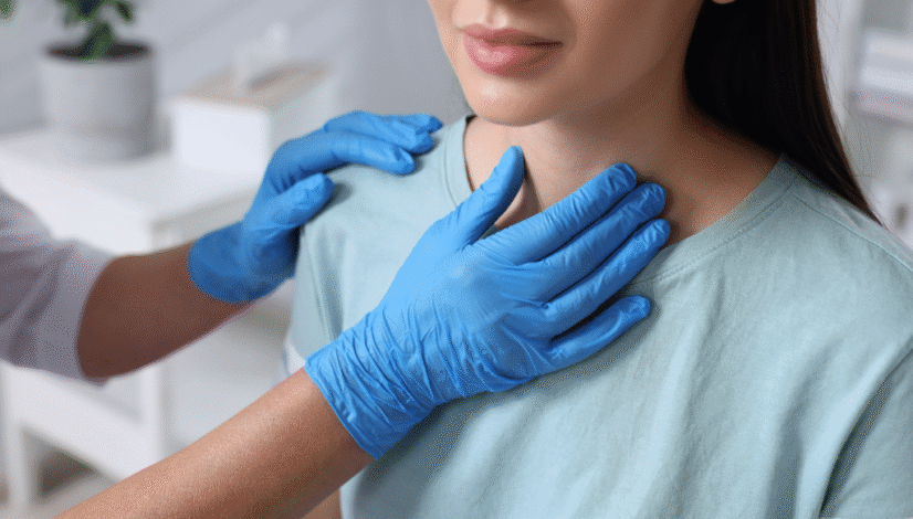 Doctor in blue gloves examining a woman’s neck, checking her thyroid gland.
