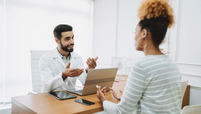 Doctor gestures while discussing something with an attentive female patient.
