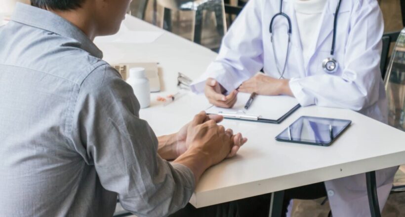 Male patient consulting with doctor at desk.