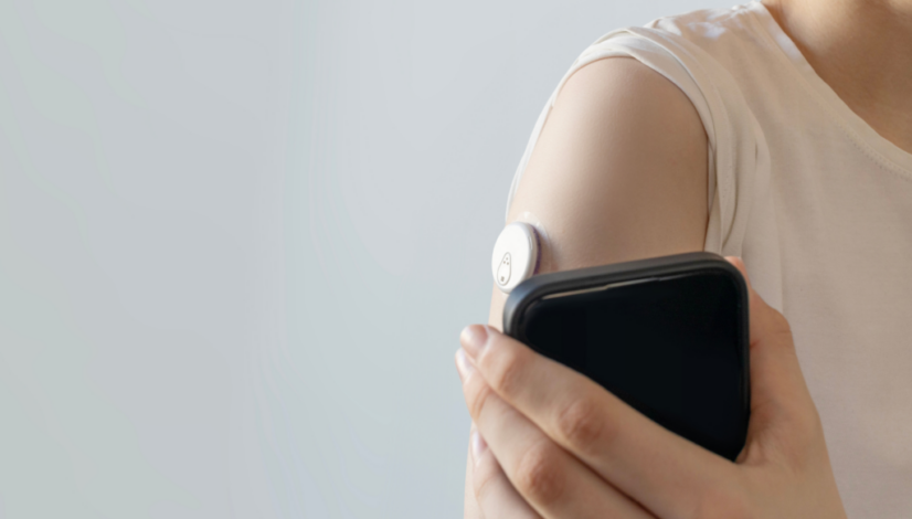 Person wearing a continuous glucose monitor sensor on their upper arm.