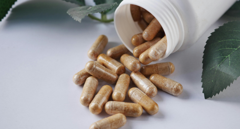 Golden-brown herbal supplement capsules spilling from a white bottle, illustrating berberine benefits.