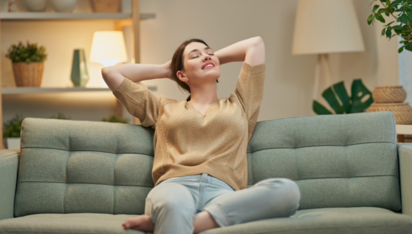 A woman relaxes contentedly on a couch, reflecting the calm benefits of environmental medicine.